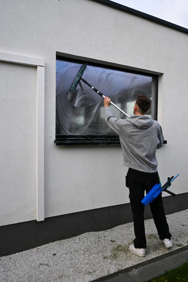 Pijls Cleaning wast een groot raam met de trekker